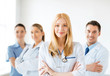 Photo: female doctor in front of medical group female doctor in front of medical group