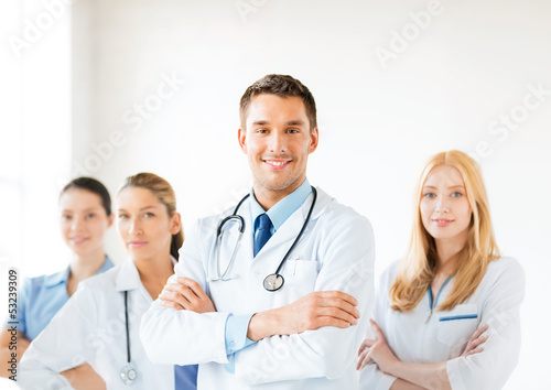 Photo: male doctor in front of medical group male doctor in front of medical group