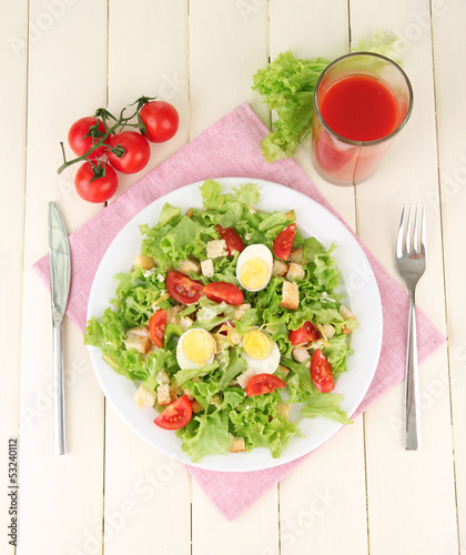 Photo: Caesar salad on white plate, on color wooden background Caesar salad on white plate, on color wooden background