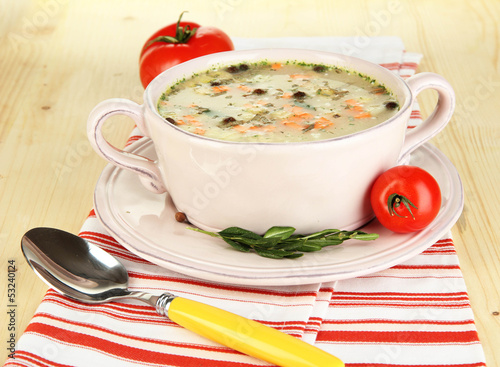 Photo: Nourishing soup in pink pan on wooden table close-up Nourishing soup in pink pan on wooden table close-up