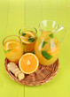 Orange lemonade in pitcher and glasses on wooden table close-up