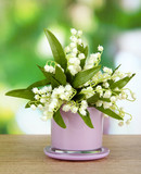 Beautiful lily of the valley in vase on nature background