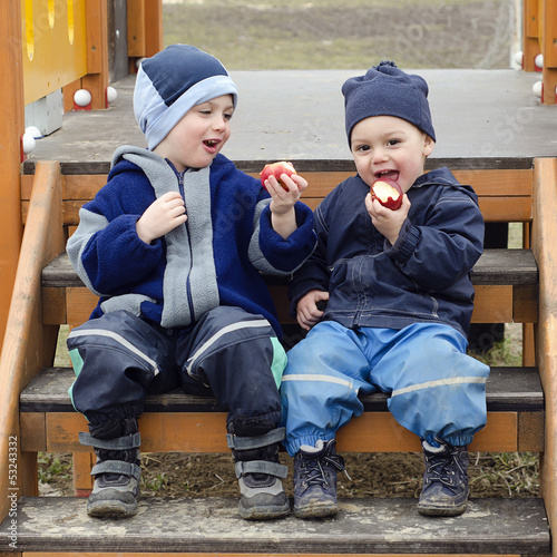 Photo: Children eating apples at playground. Children eating apples at playground.