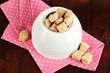 Unrefined sugar in white sugar bowl on wooden background