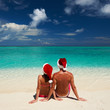 Photo: Couple in santa's hat on a beach at Maldives Couple in santa's hat on a beach at Maldives