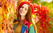 Beautiful elegant woman standing in a park in autumn