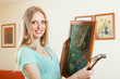 Photo: Positive blonde girl hanging pictures in frames Positive blonde girl hanging pictures in frames