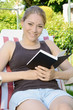 Foto: Junge Frau liest Buch im Garten Junge Frau liest Buch im Garten