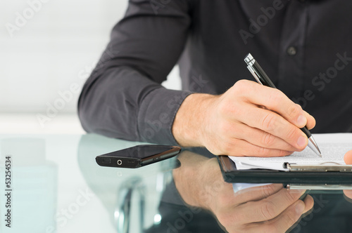 Photo: Businessman Writing a Paperwork Businessman Writing a Paperwork