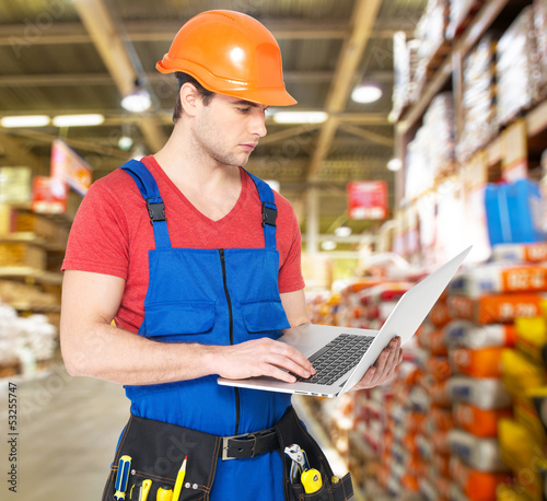 Photo: Portrait of handyman with laptop working warehouse Portrait of handyman with laptop working warehouse