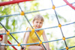 Beautiful girl climbing on rope ladder against sky