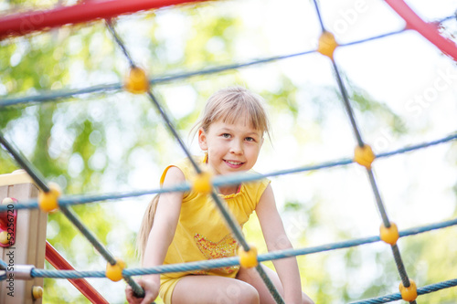 Photo: Beautiful girl climbing on rope ladder against sky Beautiful girl climbing on rope ladder against sky