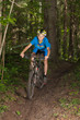 Young cyclist riding downhill in forest