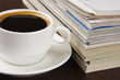 Pile of magazines and cup of coffee on table