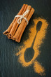Сinnamon sticks and cinnamon powder on a black chalkboard chalk