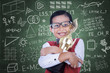 Asian boy holding trophy in class