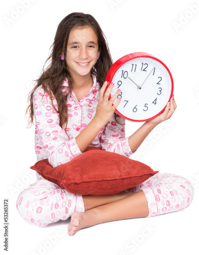 Photo: Girl wearing pajamas and holding a clock isolated on white Girl wearing pajamas and holding a clock isolated on white