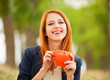 Redhead girl with orange cup at outdoor