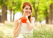 Redhead girl with orange cup at outdoor