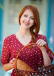 Redhead girl in red dress at outdoor near old house