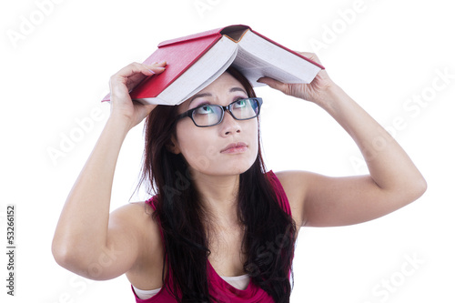 Photo: Afraid female student cover head with book - isolated Afraid female student cover head with book - isolated