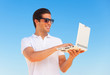 Handsome young man with laptop at beach background