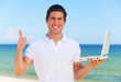 Handsome young man with laptop at beach background