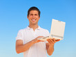 Handsome young man with laptop at blue sky background