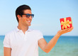 Handsome young man with gift at beach background