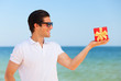 Handsome young man with gift at beach background