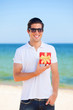 Handsome young man with gift at beach background