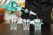 Barmen hand with bottle  pouring beverage into glasses,