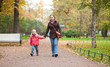 Mother with daughter walking in park by fall