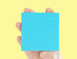 Hand holding a blue paper for notes