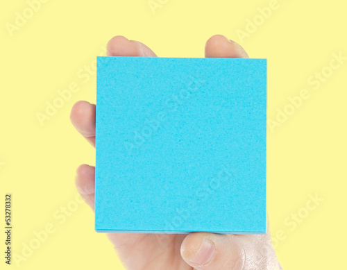 Photo: Hand holding a blue paper for notes Hand holding a blue paper for notes