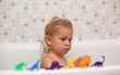 Little girl playing with toy dinosaurs in the bathtub