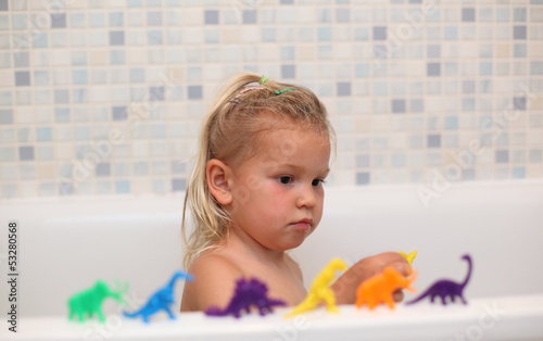 Photo: Little girl playing with toy dinosaurs in the bathtub Little girl playing with toy dinosaurs in the bathtub
