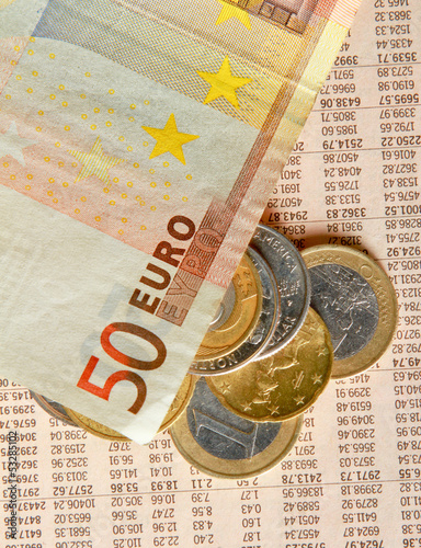 Photo: Money: euro coins and bills close up isolated on wood background Money: euro coins and bills close up isolated on wood background