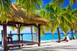 Gazebo with chairs on deserted beach with palm trees