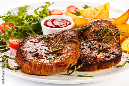Photo: Grilled steaks, baked potatoes and vegetables Grilled steaks, baked potatoes and vegetables