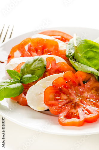 Photo: Caprese salad (fresh tomatoes, mozzarella and basil) isolated on Caprese salad (fresh tomatoes, mozzarella and basil) isolated on
