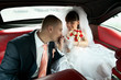 Groom kissing hand of bride inside red car