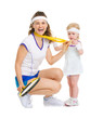 Happy mother showing baby medal for achievements in tennis