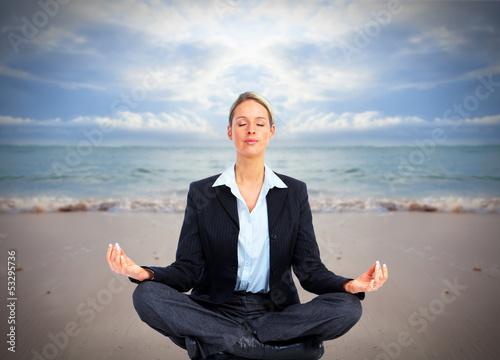Photo: Business woman doing yoga on the beach. Business woman doing yoga on the beach.