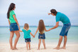 Back view of beautiful family with two kids at exotic beach