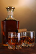Brandy with ice on wooden table on brown background