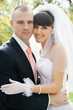 Groom and beautiful bride against blurred green leaves