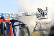 Drehleiter der Feuerwehr vor brennendem Haus