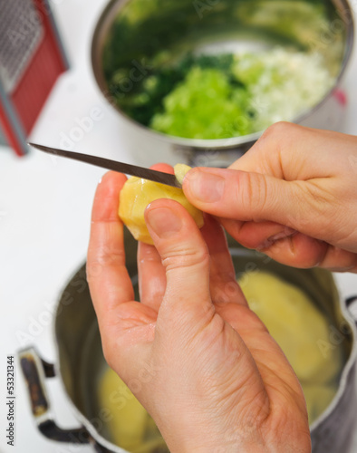 Photo: Woman cutting to peel potatoes. Kitchen working. Prepare food Woman cutting to peel potatoes. Kitchen working. Prepare food