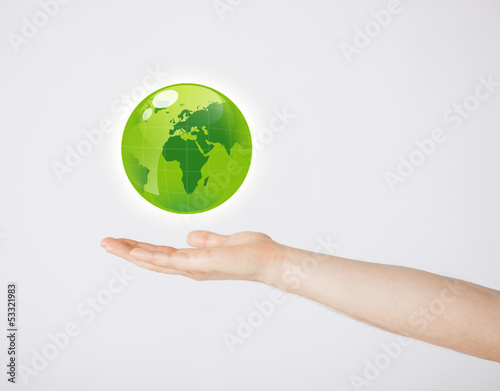 Photo: mans hand holding green globe mans hand holding green globe